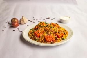 Mughlai Chicken Paneer tikka Biryani rice pulao with garlic, onion and raita served in plate isolated on background side view of indian and pakistani traditional food photo