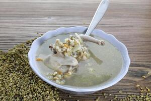 Pigeon soup with corn and wheat served in bowl isolated on wooden table side view of arabic food photo