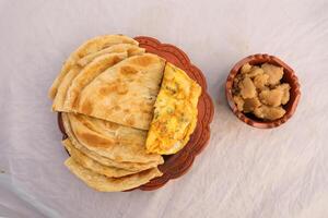 desi desayuno tortilla, halwa y paratha servido en plato aislado en antecedentes parte superior ver de bangladesi desayuno foto