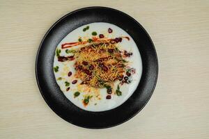 Doi Papri Chaat, papdi, dahi bhalla, bhallay, potato, crackers, masala and yogurt served in plate isolated on background top view of indian spices street food photo