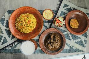 Haash Bhuna Khichuri Combo with egg plant, korma karahi, meat, salad, borhani and firni served in dish isolated on mat top view of indian and bangladeshi food photo