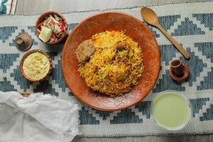 Mutton Kacchi biryani with salad, borhani and Chui Pitha served in dish isolated on mat top view of indian and bangladeshi food photo