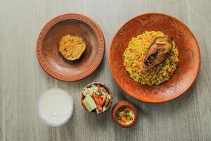 Hilsa Khichuri Combo with salad, eggplant, borhani and boondi rabi served in dish isolated on mat top view of indian and bangladeshi food photo