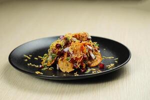 Aloo Papri Chaat, dahi bhalla, bhallay, potato, crackers, masala and yogurt served in plate isolated on background top view of indian spices street food photo