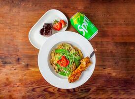 vegetable aglio e olio with baby corn, mushroom and tomato with chicken satay, brownie and sprite can 330 ml served in dish isolated on wooden table top view of hong kong food photo