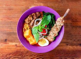 beef noodle soup with skewer served in dish isolated on wooden table top view of hong kong food photo