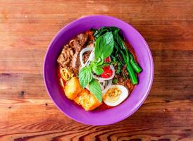 beef noodle soup with egg, onion and tomato served in dish isolated on wooden table top view of hong kong food photo