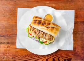 baguette sandwich burger willed with chicken, cucumber, tomato, onion and mayonnaise dip served in dish isolated on wooden table top view of hong kong food photo