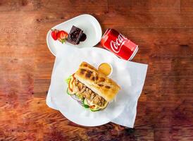 baguette sandwich burger willed with chicken, cucumber, tomato, onion and mayonnaise dip, brownie and coke can 330 ml served in dish isolated on wooden table top view of hong kong food photo