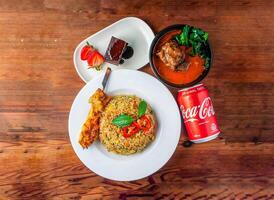 garlic fried rice with skewer, chicken satay, brownie and coke can 330 ml served in dish isolated on wooden table top view of hong kong food photo