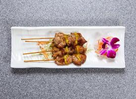 Chicken satay sticks served in dish isolated on grey background top view of hong kong food photo