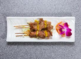 Cerdo satay palos servido en plato aislado en gris antecedentes parte superior ver de hong kong comida foto