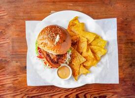 Pig burger with cucumber, tomato and cabbage, mayonnaise dip and crackers served in dish isolated on wooden table top view of hong kong food photo