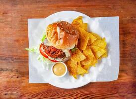 Satay chicken burger with cucumber, tomato and cabbage, mayonnaise dip and crackers served in dish isolated on wooden table top view of hong kong food photo