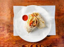 Chicken wrap filled with cucumber, onion and tomato with chilli sauce served in dish isolated on wooden table top view of hong kong food photo