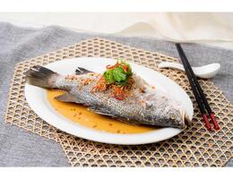 STEAMED SEA BASS IN HK STYLE with chopsticks served in dish isolated on table top view of singapore food photo
