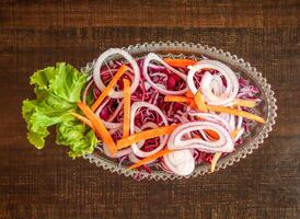 Salad with cabbage onion, lettuce leaf and carrot served in dish isolated on wooden background top view of healthy organic food photo