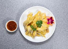 Whole hai nam chicken in thai style with chili sauce served in dish isolated on grey background top view of hong kong food photo