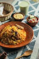 Mutton Kacchi biryani with salad, borhani and Chui Pitha served in dish isolated on mat top view of indian and bangladeshi food photo