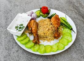 vapor pollo pierna pedazo Biryani pulao arroz con ensalada y raita servido en plato aislado en antecedentes parte superior ver de indio especias y pakistaní comida foto