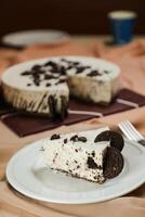 Oreo Cheesecake slice include chocolate, cream, sugar with fork and flowers served in plate isolated on napkin side view of cafe food photo