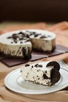 Oreo Cheesecake slice include chocolate, cream, sugar with fork and flowers served in plate isolated on napkin side view of cafe food photo