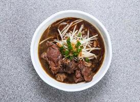 thai rice noodle in soup with beef flank served in dish isolated on grey background top view of hong kong food photo