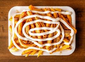 mayonesa papas fritas con condimento o patata papas fritas cargado con mayonesa servido en plato aislado en de madera antecedentes parte superior ver de indio especias y pakistaní comida foto