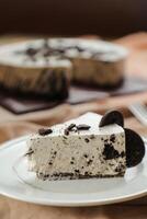 Oreo Cheesecake slice include chocolate, cream, sugar with fork and flowers served in plate isolated on napkin side view of cafe food photo