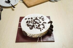 Oreo Cheesecake include chocolate, cream, sugar with fork and flowers served on board isolated on napkin side view of cafe food photo