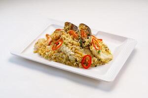 Seafood fried rice include seashell, octopus, prawn shrimp and tomato served in dish isolated on wooden table side view of hong kong fast food photo