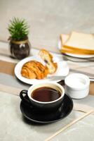 Americano coffee served in cup with croissant, puff pastry, bread and knife isolated on napkin side view cafe breakfast photo