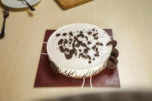 Oreo Cheesecake include chocolate, cream, sugar with fork and flowers served on board isolated on napkin side view of cafe food photo