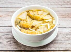 noodles with shrimp dumpling served in dish isolated on wooden table top view hong kong food photo