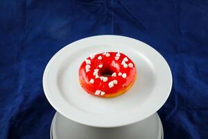 Strawberry Glazed Donut served in plate isolated on blue background side view of baked food breakfast on table photo