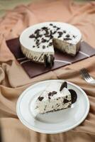 Oreo Cheesecake slice include chocolate, cream, sugar with fork and flowers served in plate isolated on napkin side view of cafe food photo