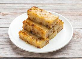 fried white turnip cake served in dish isolated on wooden table top view hong kong food photo