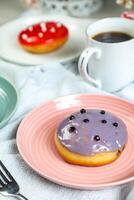 Fresh Blueberry Donut with cup of coffee served in plate Isolated on napkin side view of baked breakfast food photo