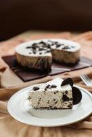 Oreo Cheesecake slice include chocolate, cream, sugar with fork and flowers served in plate isolated on napkin side view of cafe food photo