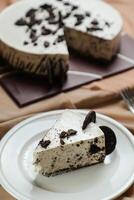 Oreo Cheesecake slice include chocolate, cream, sugar with fork and flowers served in plate isolated on napkin side view of cafe food photo