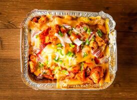 pizza loaded fries served in dish isolated on wooden background top view of indian spices and pakistani food photo