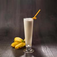 Banana Milkshake with straw served in glass isolated on table side view healthy morning drink photo
