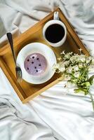 Fresh Blueberry Donut with cup of coffee, fork and flowers served in plate Isolated on napkin side view of baked breakfast food photo