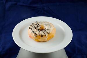 White Chocolate Donut served in plate isolated on blue background side view of baked food breakfast on table photo