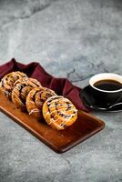 Chocolate Roll served on wooden board with cup of black coffee isolated on napkin side view of french breakfast baked food item photo