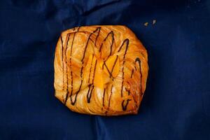 Peach Danish pastry puff isolated on blue napkin top view of french breakfast baked food item photo