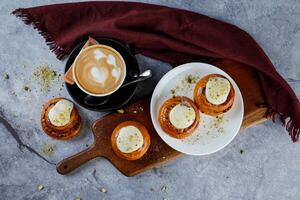 Cinnamon Roll served on wooden board with cup of coffee latte art isolated on napkin top view of french breakfast baked food item photo