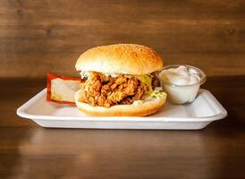 Crispy Chicken Zinger Burger with ketchup and mayonnaise dip served in dish isolated on wooden background side view of indian spices and pakistani food photo