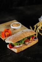 ciabatta ahumado jamón emparedado aislado en de madera con mayonesa inmersión y francés papas fritas Cubeta tablero lado ver de italiano rápido comida en gris antecedentes foto