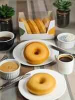 Plain Donuts with dip and cup of coffee isolated on napkin side view of baked food breakfast on table photo